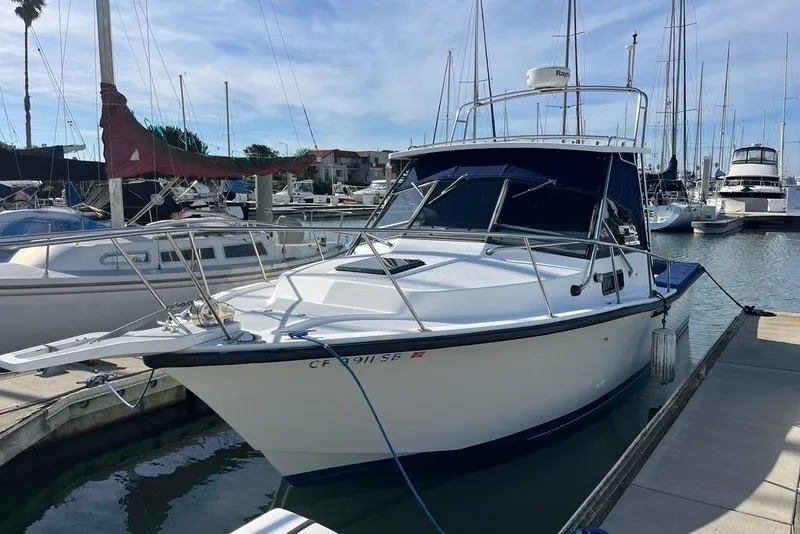 The Image of 1992 Rampage 28 Sportsman boat docked in a marina under a clear blue sky. - 1