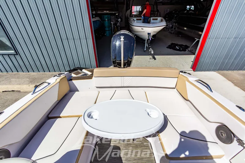 Slide: The Image of 2019 Glastron GTD 180 boat interior with seating and table, docked near a marina. - 14