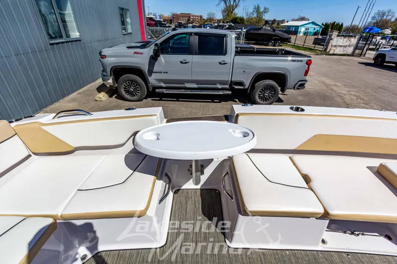 Slide: The Image of 2019 Glastron GTD 180 boat interior with seating and table, parked beside a gray pickup truck. - 16