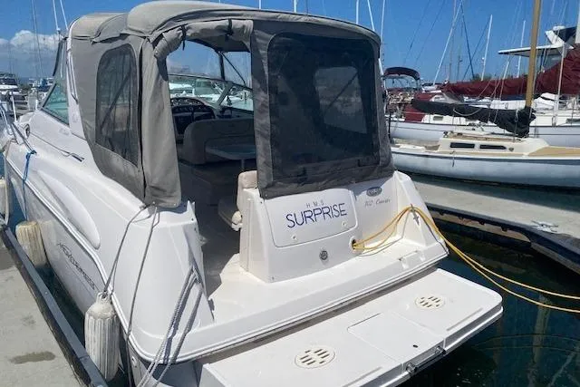 Slide: The Image of 2001 Monterey 302 Cruiser docked at marina, featuring covered cockpit and visible boat name "Surprise". - 2
