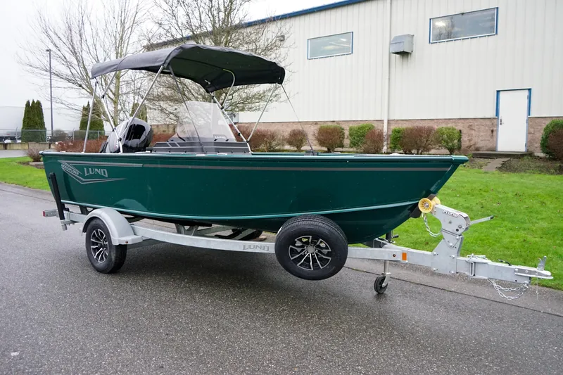 The Image of 2026 Lund 1800 Explorer SS boat on trailer, green, parked outside building. - 1