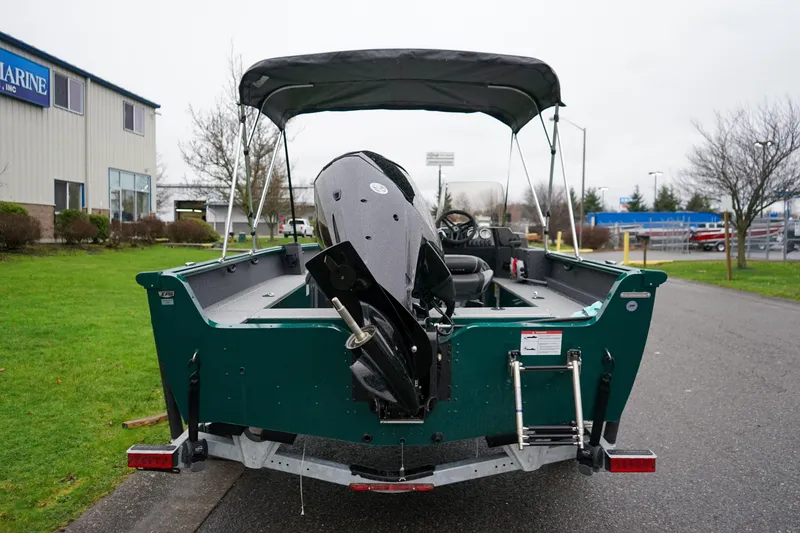 Slide: The Image of 2026 Lund 1800 Explorer Sport boat with canopy, parked outdoors near a building. - 4