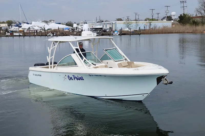 Slide: The Image of 2017 Sailfish 275 DC boat cruising on calm waters near a marina. - 6