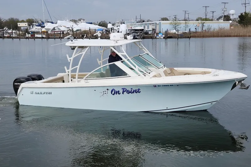 Slide: The Image of 2017 Sailfish 275 DC boat cruising on calm water near a marina. - 9