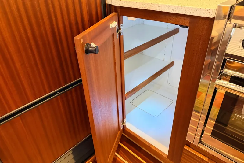 Slide: The Image of Open wooden cabinet with shelves inside American Tug 365, 2022 model. - 10