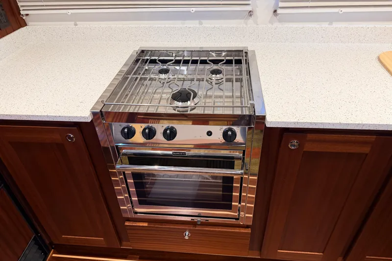 Slide: The Image of Modern kitchen stove in 2022 American Tug 365 boat, featuring sleek design and wooden cabinetry. - 11