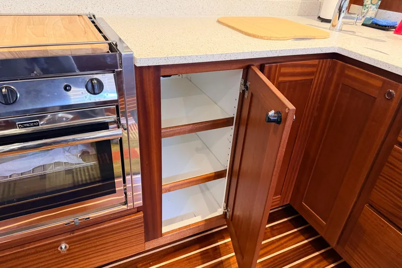 Slide: The Image of Kitchen area of a 2022 American Tug 365 with open wooden cabinets and a stainless steel oven. - 13