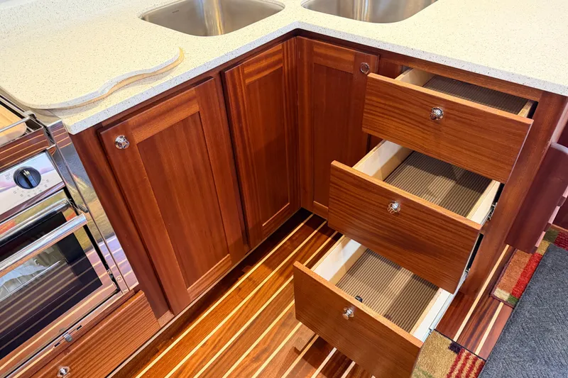 Slide: The Image of American Tug 365 (2022) kitchen with wooden cabinets, open drawers, and stainless steel sink. - 16