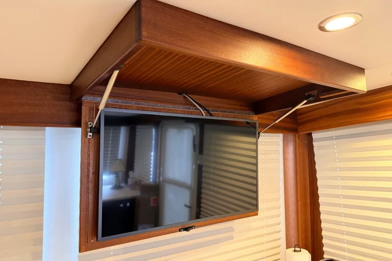 Slide: The Image of 2022 American Tug 365 interior with mounted TV and wooden cabinetry. - 19