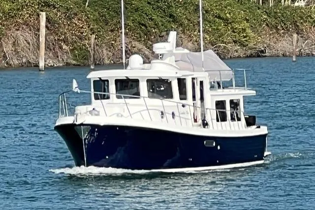 Slide: The Image of 2022 American Tug 365 cruising on a serene waterway, surrounded by lush greenery. - 2