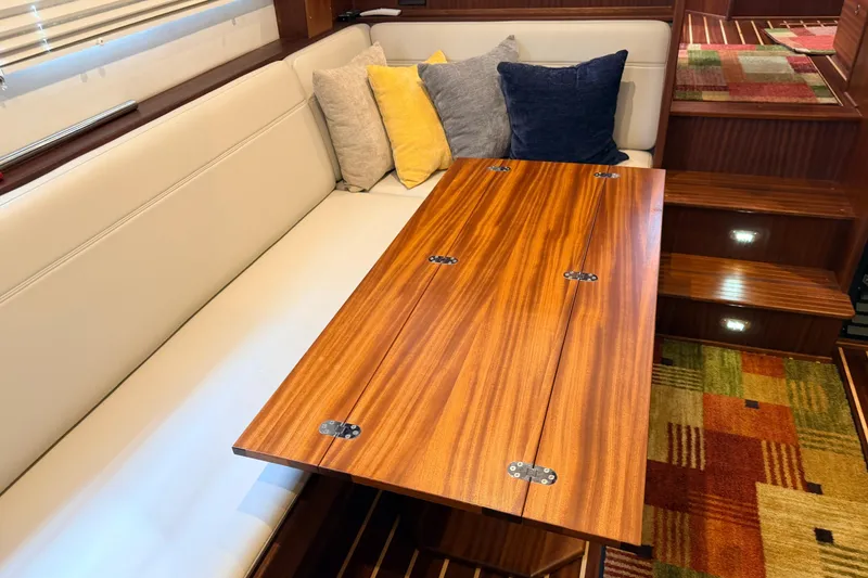 Slide: The Image of Interior of 2022 American Tug 365 with wooden table, cushioned seating, and colorful pillows. - 5