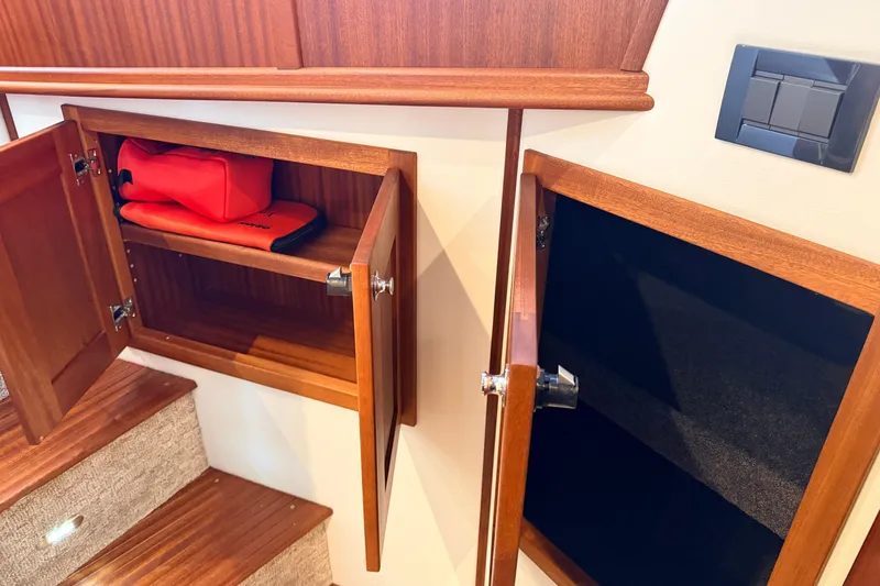 Slide: The Image of Interior storage cabinets on 2022 American Tug 365 boat, featuring wooden finish and safety equipment. - 50