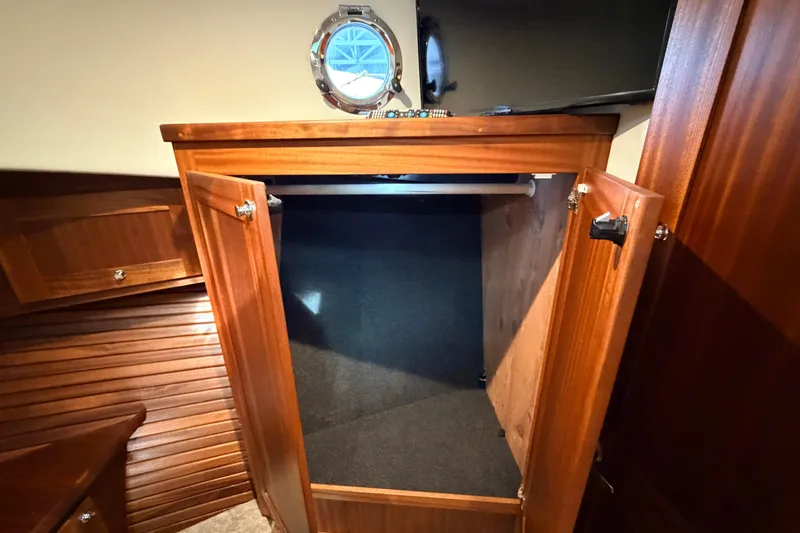 Slide: The Image of Wooden cabinet interior on 2022 American Tug 365 boat, featuring open doors and a porthole. - 56