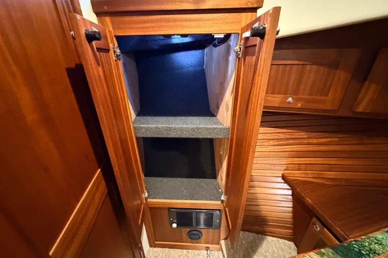Slide: The Image of Interior storage cabinet in 2022 American Tug 365 boat, featuring wooden shelves and lighting. - 58