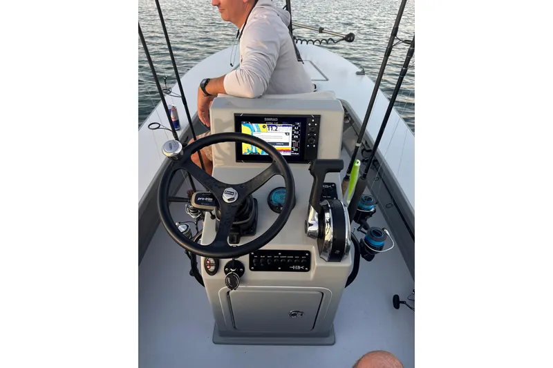 Slide: The Image of 2024 Hell's Bay Marathon boat console with steering wheel, fishing rods, and navigation display. - 2