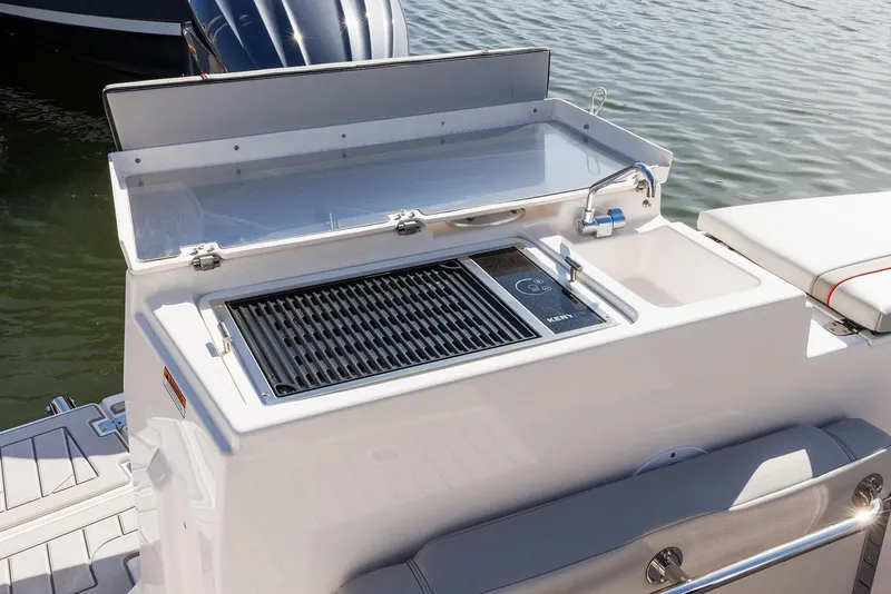 Slide: The Image of Manufacturer Provided Image: Outdoor grill and sink on 2025 Solara S-250 Coupe boat, docked by the water. - 12
