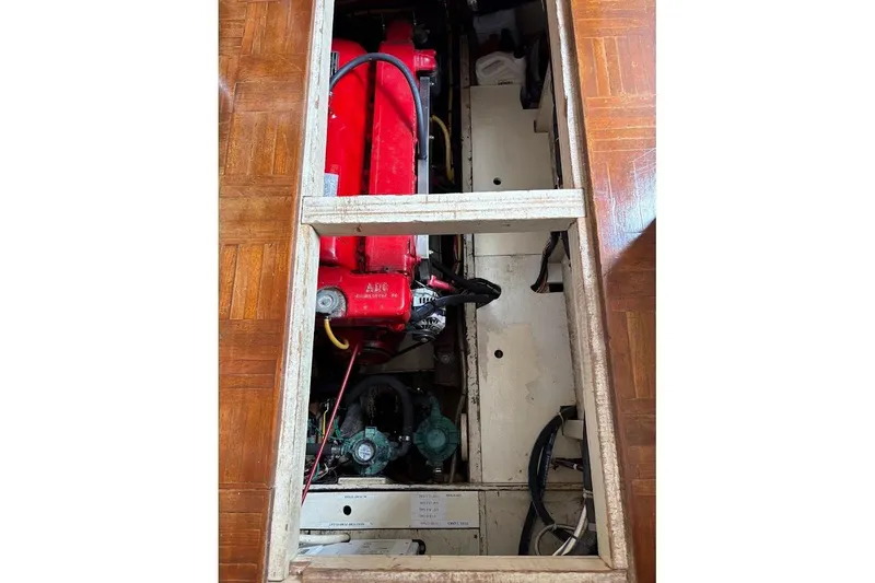 Slide: The Image of Engine compartment of a 1987 Albin 36 Trawler, featuring a red engine and wooden flooring. - 19