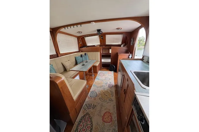 Slide: The Image of Interior of 1987 Albin 36 Trawler with cozy seating, table, and kitchenette. - 2