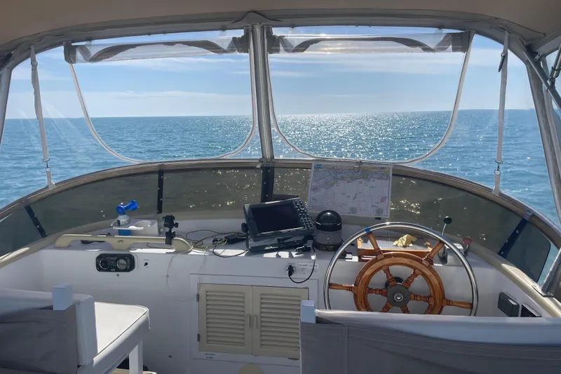Slide: The Image of Helm of 1987 Albin 36 Trawler with ocean view, featuring navigation equipment and wooden steering wheel. - 30