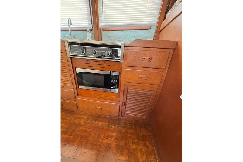 Slide: The Image of 1987 Albin 36 Trawler kitchen with stove, microwave, and wooden cabinetry. - 6