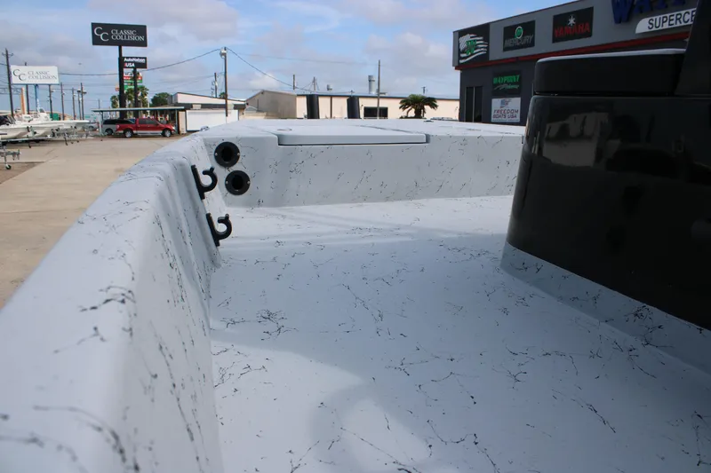 Slide: The Image of 2026 Freedom Boats 21' Commander interior with marbled design, docked at a dealership. - 12