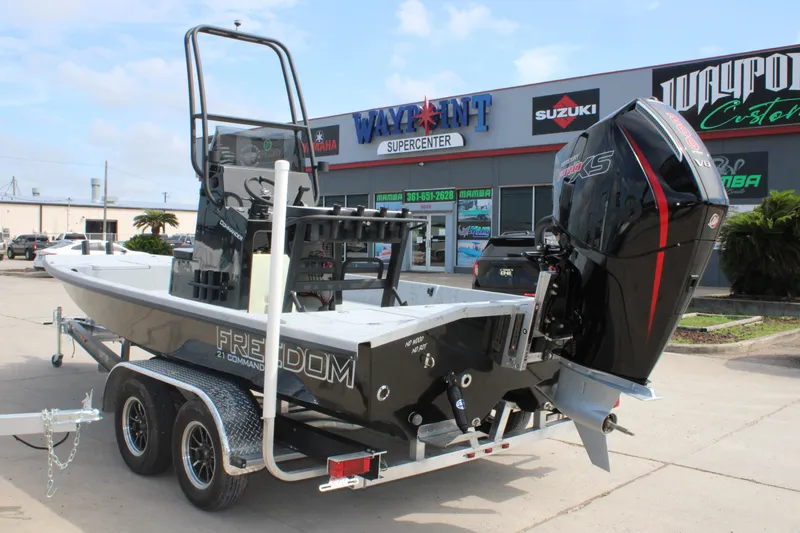 Slide: The Image of 2026 Freedom Boats 21' Commander on trailer, parked outside dealership with visible signage. - 2