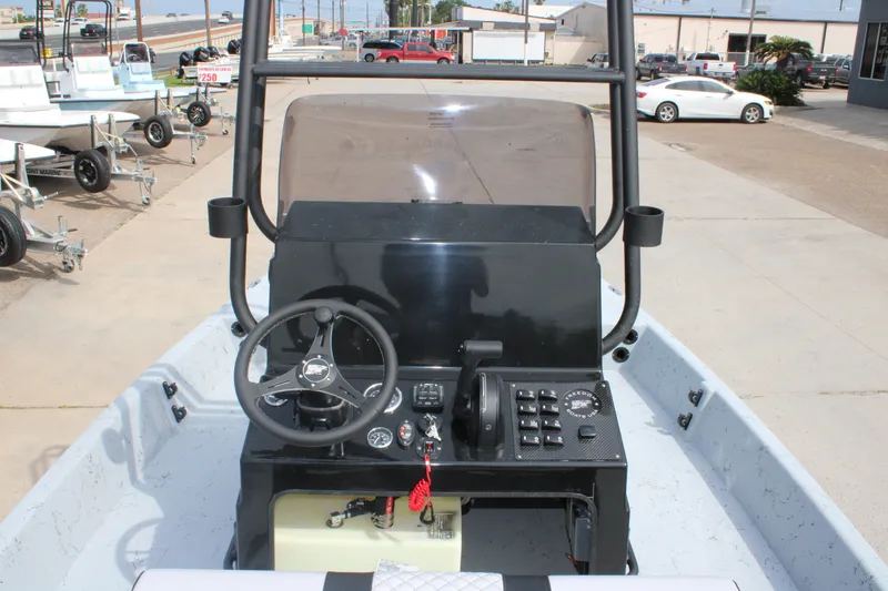 Slide: The Image of 2026 Freedom Boats 21' Commander dashboard with steering wheel and controls, parked outdoors. - 7
