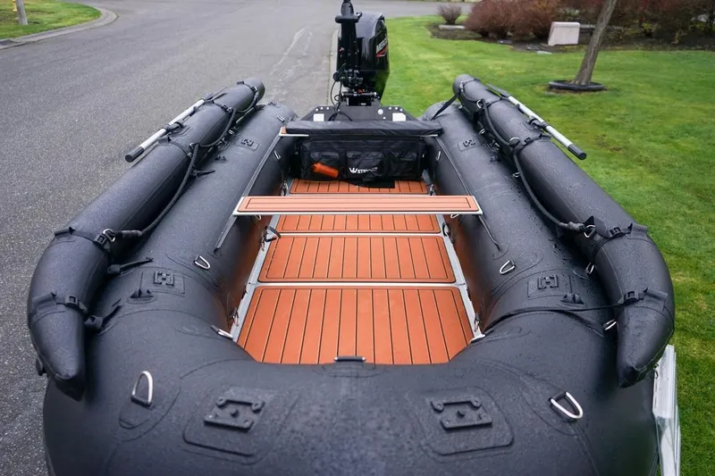 Slide: The Image of Stryker Tunnel JET PRO 470 inflatable boat, 2025 model, with wooden deck, parked on grass. - 7