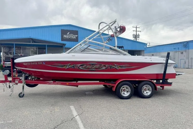 The Image of 2006 Tigé 22Ve boat on trailer, parked outside a blue building. - 1