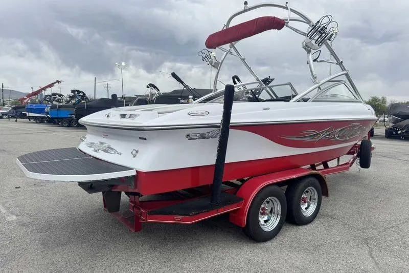 Slide: The Image of 2006 Tigé 22Ve boat on trailer, red and white design, parked outdoors. - 5