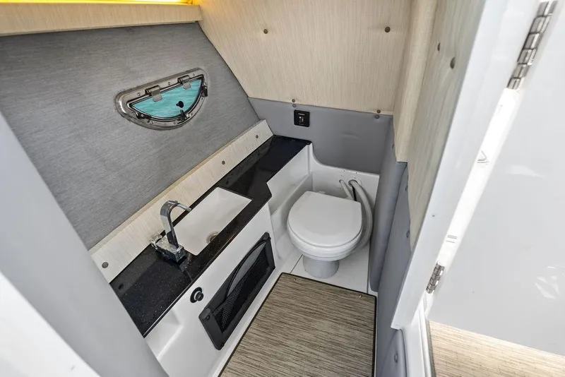 Slide: The Image of 2022 Cobalt R8 Outboard boat bathroom with sink, toilet, and porthole window. - 18