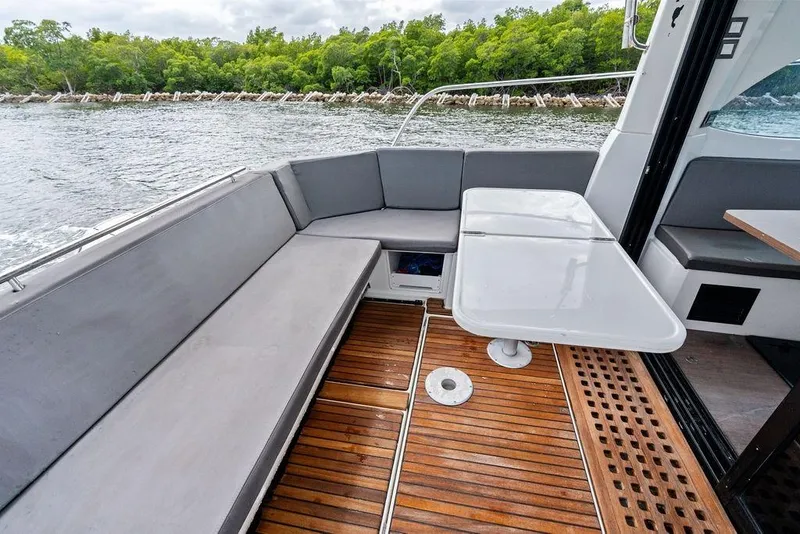 Slide: The Image of 2022 Beneteau Antares 11 boat interior with seating and table, overlooking water and greenery. - 26