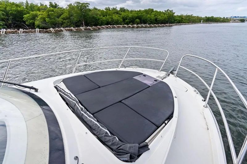 Slide: The Image of Bow view of 2022 Beneteau Antares 11 with sunpad, surrounded by calm waters and lush greenery. - 27