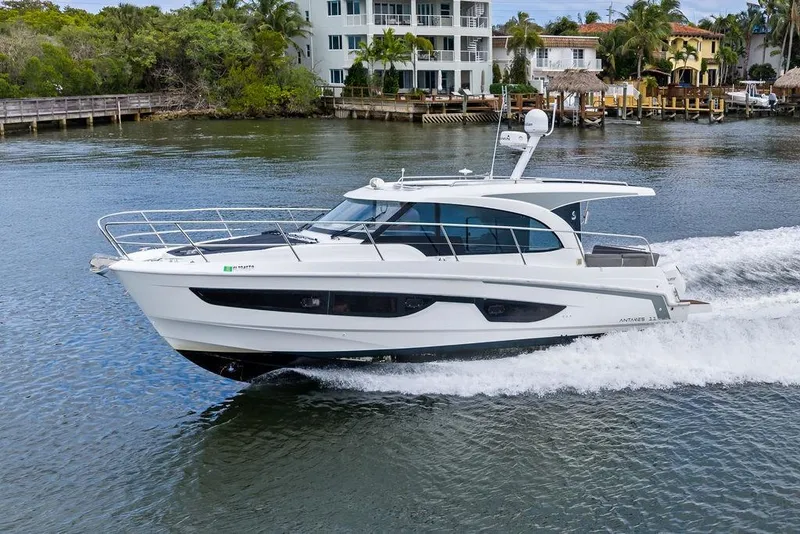 Slide: The Image of 2022 Beneteau Antares 11 cruising on a scenic waterway near luxury homes. - 4