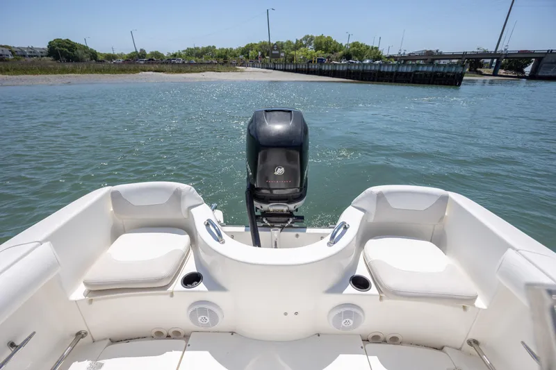 Slide: The Image of 2006 Boston Whaler 210 Outrage boat with seating and outboard motor on calm water. - 12