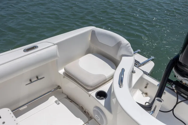 Slide: The Image of 2006 Boston Whaler 210 Outrage boat interior with cushioned seating by the water. - 13