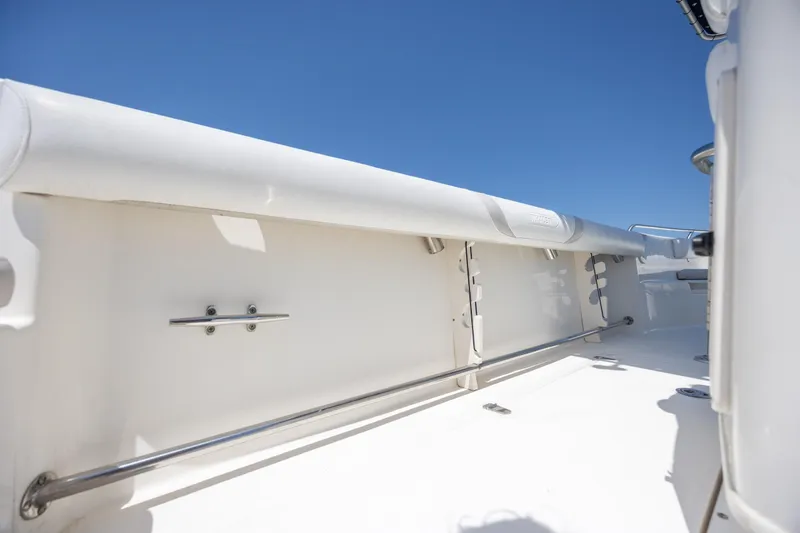 Slide: The Image of 2006 Boston Whaler 210 Outrage boat interior with white railing and clear blue sky. - 23