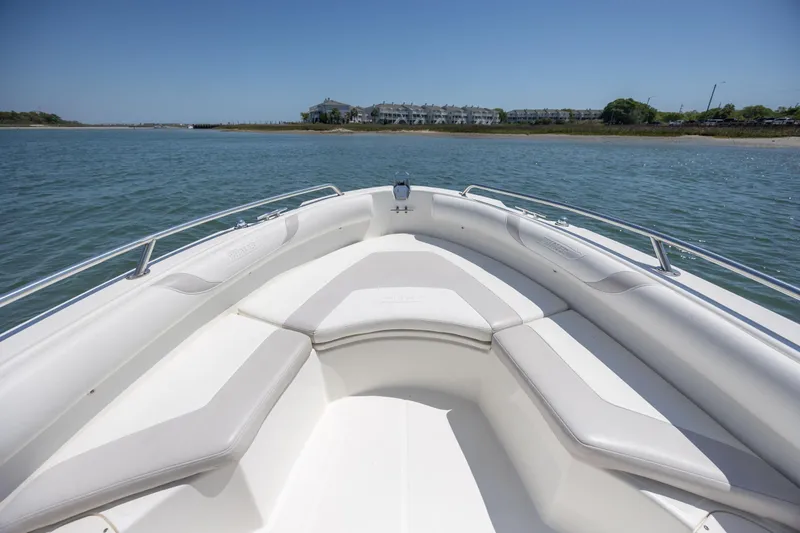 Slide: The Image of 2006 Boston Whaler 210 Outrage boat interior with cushioned seating on calm water. - 25