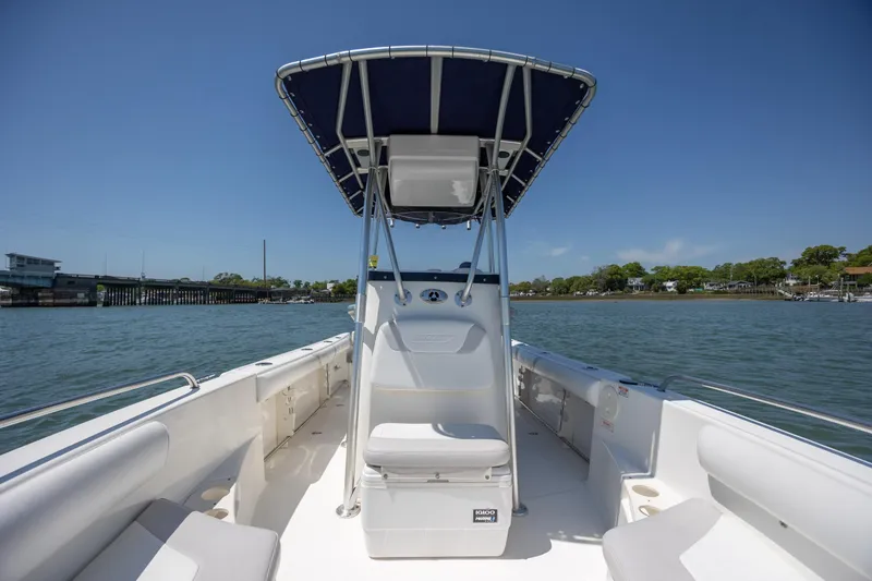 Slide: The Image of 2006 Boston Whaler 210 Outrage boat on water, featuring spacious deck and canopy. - 26