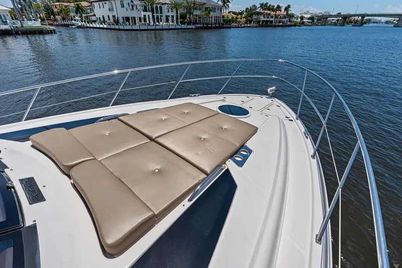 Slide: The Image of 2013 Regal 42 Sport Coupe yacht with sunpad on deck, overlooking serene waterfront. - 13