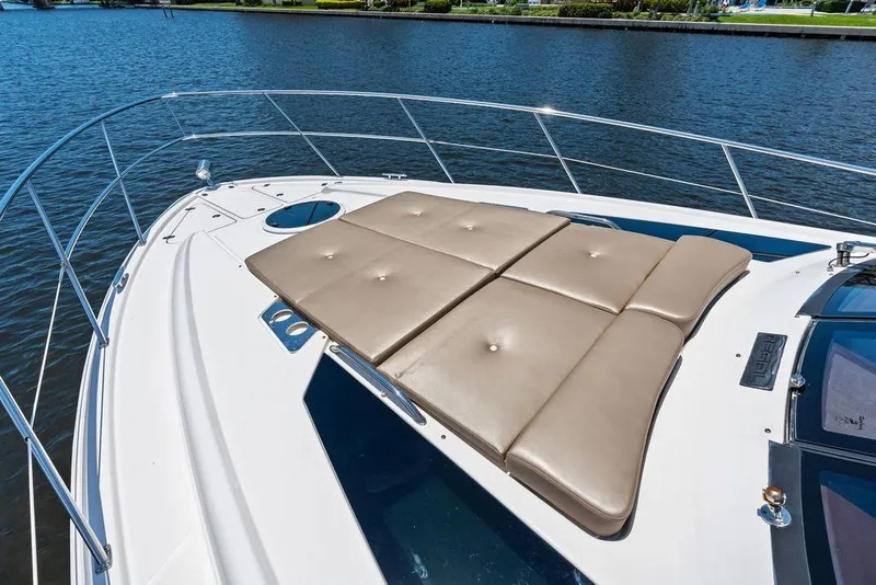 Slide: The Image of 2013 Regal 42 Sport Coupe yacht with sunpad on deck, docked by calm waters. - 15