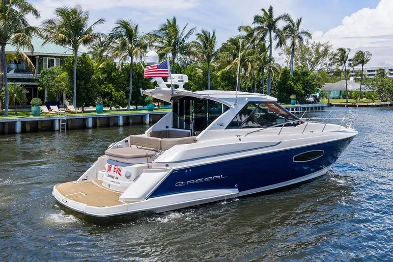 Slide: The Image of 2013 Regal 42 Sport Coupe yacht cruising on a sunny day, surrounded by palm trees. - 2