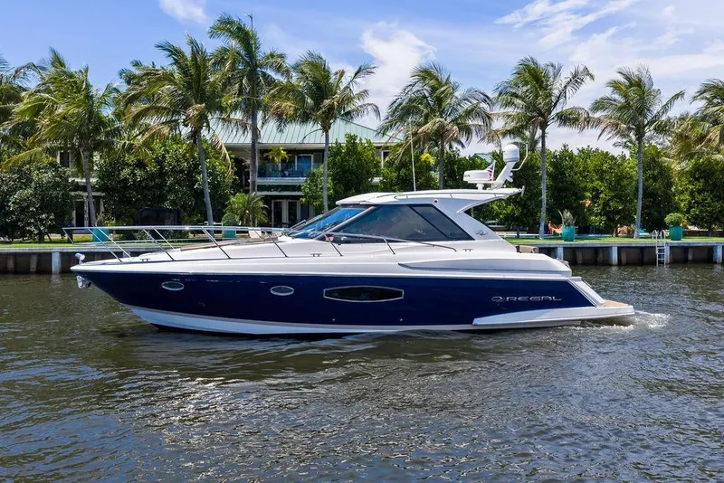 Slide: The Image of 2013 Regal 42 Sport Coupe yacht cruising on a sunny day with palm trees in the background. - 3