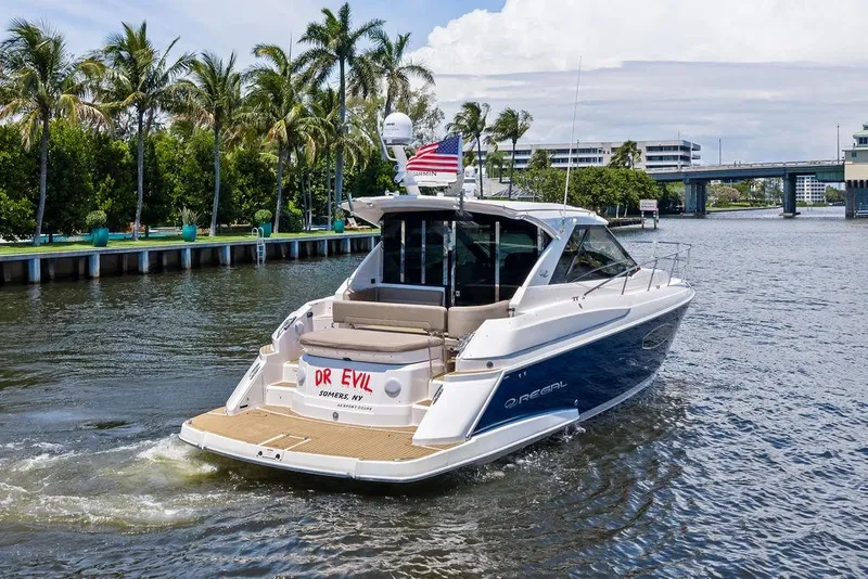 Slide: The Image of 2013 Regal 42 Sport Coupe yacht cruising on a scenic waterway with palm trees. - 4