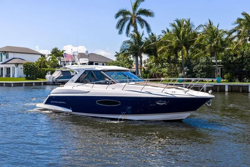 Slide: The Image of 2013 Regal 42 Sport Coupe yacht cruising on a sunny day near palm trees and waterfront homes. - 7