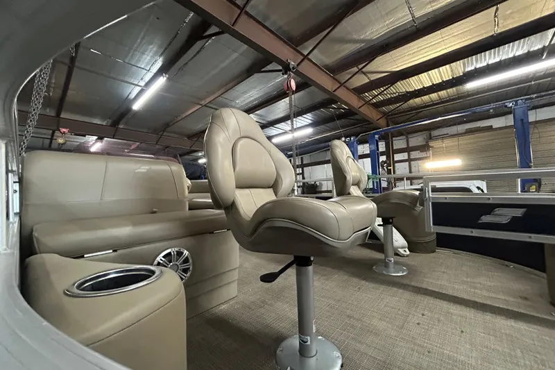 Slide: The Image of 2023 Starcraft LX 18 F boat interior with beige seating and modern design in a warehouse. - 12
