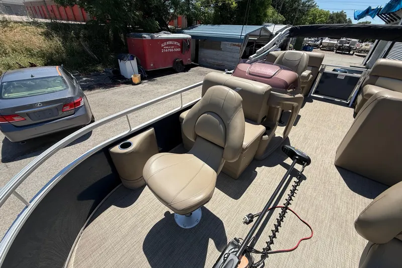 Slide: The Image of 2023 Starcraft LX 18 F pontoon boat interior with beige seating and steering console. - 23