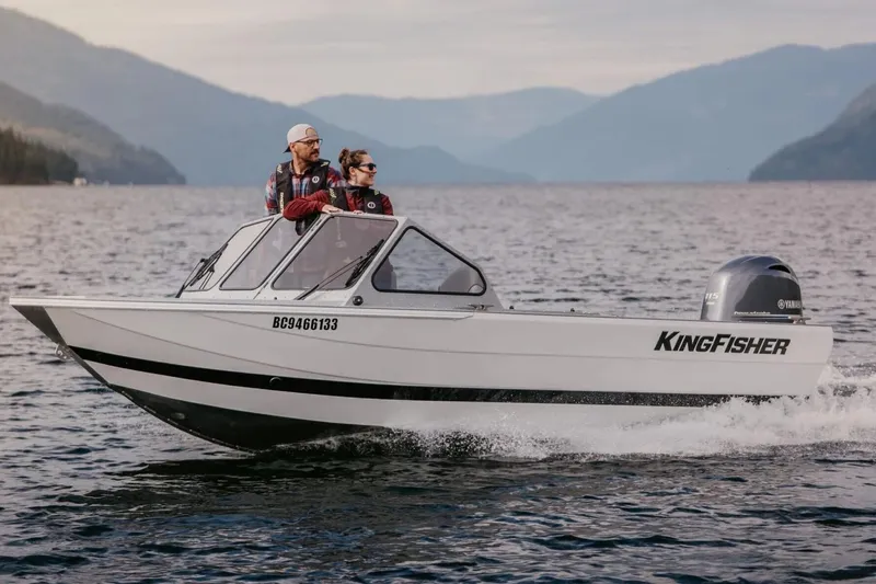 The Image of 2026 KingFisher 1825 Falcon boat cruising on a scenic lake with two passengers. - 1