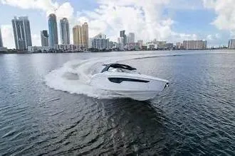 Slide: The Image of 2021 Cruisers Yachts 38 GLS OB speeding on water with city skyline backdrop. - 3