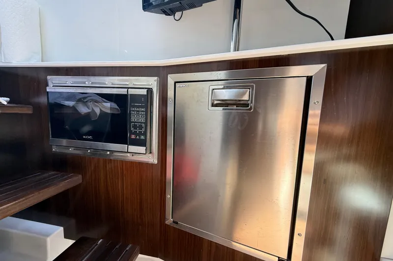 Slide: The Image of Interior of 2021 Cruisers Yachts 38 GLS OB featuring a microwave and stainless steel appliance. - 59